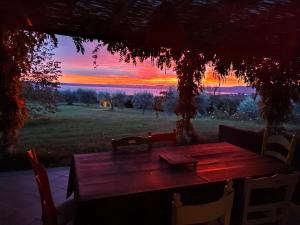 une table en bois avec des chaises et un coucher de soleil en arrière-plan dans l'établissement Villa Fonte Tartaruga Trevignano Romano, à Trevignano Romano