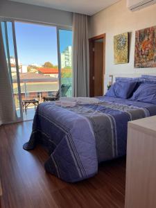 a bedroom with a large bed and a balcony at Suite Montparnasse in Lagoa Santa