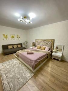 a bedroom with a large bed and a couch at 1-комнатная квартира в районе Космос in Aktobe