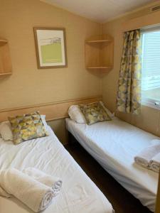two beds in a small room with a window at Newquay Bay Porth Caravan - 8 Berth in Newquay