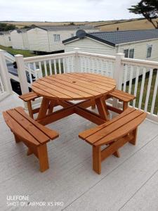 a wooden picnic table and two benches on a deck at Newquay Bay Porth Caravan - 8 Berth in Newquay