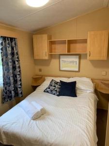 una camera da letto con un grande letto bianco con cuscini blu di Newquay Bay Porth Caravan - 8 Berth a Newquay