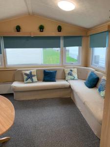 uma sala de estar com um sofá com almofadas azuis em Newquay Bay Porth Caravan - 8 Berth em Newquay