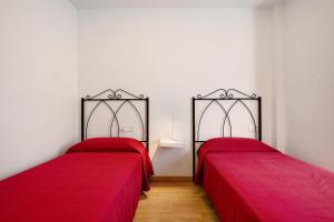 - 2 lits dans une chambre avec des draps rouges dans l'établissement Apartamento Playa Morro Jable 1a, à Morro del Jable