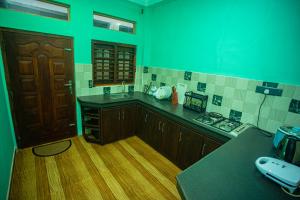 cocina con paredes verdes, suelo de madera y encimera en DR. Place en Hikkaduwa
