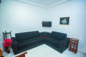 sala de estar con sofá negro y TV en DR. Place en Hikkaduwa