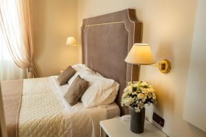 Un dormitorio con una cama y una mesa con un jarrón de flores en Hotel Rosa Dei Venti, en Lerici