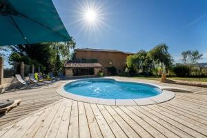 - une piscine sur une terrasse en bois avec un parasol dans l'établissement Les Sarments du Beaujolais, calme proche Lyon, à Sarcey