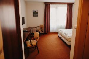 a hotel room with a bed and a table and chairs at Golf Hotel Austerlitz in Slavkov u Brna