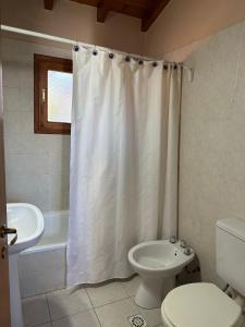 uma casa de banho com um lavatório de WC e uma cortina de chuveiro em Casita Roca em San Martín de los Andes