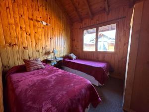 una camera con 2 letti in una cabina di legno di Casita Roca a San Martín de los Andes