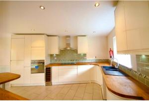 a kitchen with white cabinets and a wooden counter top at Stunning 5-Bed House in Peterborough host 15 g in Peterborough