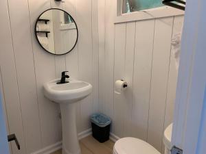 een witte badkamer met een wastafel en een spiegel bij Motel Luzerne in Lake Luzerne