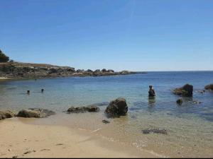 un hombre sentado en el agua en una playa en Logement indépendant avec extérieur privatif et clôturé, en Batz-sur-Mer