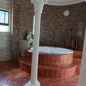a bath tub in a room with a brick wall at Beachcomber Bay Guest House In South Africa in Margate