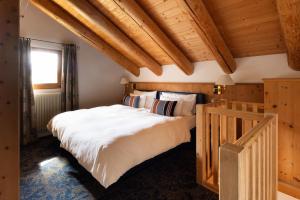 a bedroom with a large white bed and wooden ceilings at Hotel Chesa Rosatsch - Home of Food in Celerina