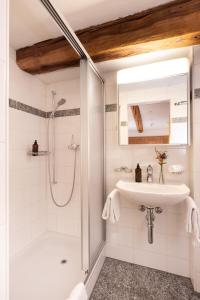a white bathroom with a shower and a sink at Hotel Chesa Rosatsch - Home of Food in Celerina