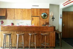 eine Küche mit einer Holztheke mit Hockern um sie herum in der Unterkunft Sunny 2 BR w large terrace, stunning views & pool in Crans-Montana