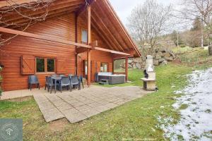 a house with a table and chairs in front of it at Chalet Les Brimbelles avec Jacuzzi in Gérardmer