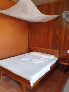 Ce lit se trouve dans un dortoir doté d'un filet sur le mur. dans l'établissement Ba Linh Homestay, à Vĩnh Long