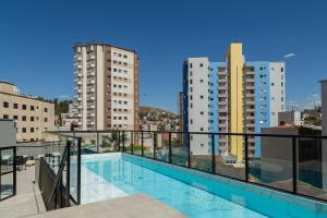 balcón con piscina y edificios en Maravilhoso e elegante studio para casal PGO412, en Poços de Caldas