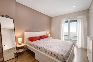 a bedroom with a bed with red pillows and a window at Sunset Holiday Home in Fernao Ferro +22 photos