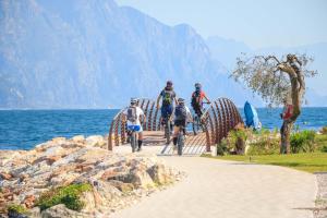 a group of people riding bikes on a bridge over the water at Appartamento alla Playa in Brenzone sul Garda