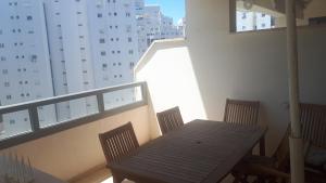 een houten tafel en stoelen op een balkon met een gebouw bij Haatsmaout City center apartment Ashdod in Ashdod