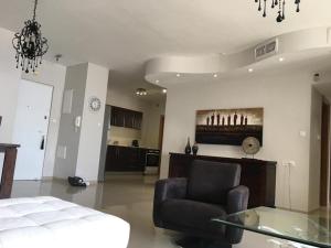 Haatsmaout City center apartment Ashdod في أشدود: غرفة معيشة مع كرسي وطاولة زجاجية