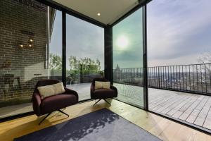 Duas cadeiras sentadas numa varanda com janelas grandes em 12A, Luxe & Uniek - Bioscoopzaal - Terras - Uitzicht em Oisterwijk