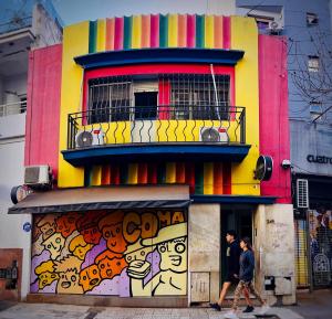 dos personas caminando por un colorido edificio con graffiti en Lacandona Hostel en Córdoba