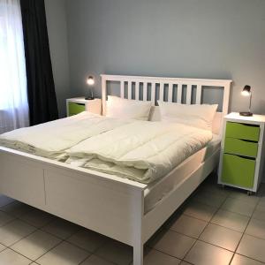 um quarto com uma cama branca com duas mesas de cabeceira em Ferienwohnung-Fehmarnsund em Petersdorf auf Fehmarn