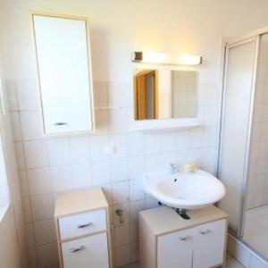 uma casa de banho branca com um lavatório e um espelho em Ferienwohnung-Fehmarnsund em Petersdorf auf Fehmarn