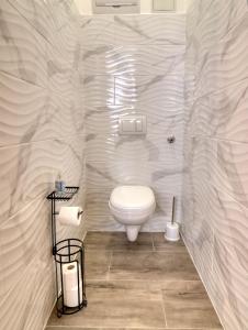 a white bathroom with a toilet in a room at Nyírfa-Lak Apartman in Szilvásvárad