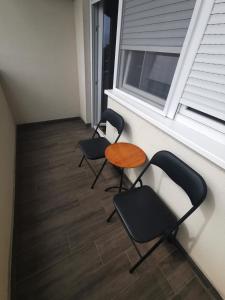 two chairs and a table in front of a window at Gold Apartman in Subotica