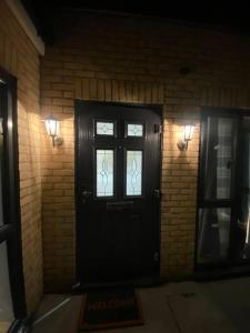 a black door with a window on a brick wall at Holiday Home, Sleep 10 in London in South Norwood