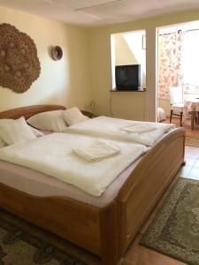 1 cama grande en un dormitorio con TV en la pared en Talizmán Étterem Panzió en Miskolc
