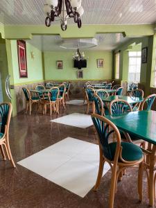 ein Esszimmer mit grünen Wänden, Tischen und Stühlen in der Unterkunft Penuel Plaza Hotel in Kimana