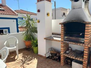 a outdoor fireplace on a patio with a table and chairs at Casa com Cor in Zambujeira do Mar