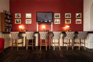 a bar with stools in a room with red walls at Palmers Lodge Swiss Cottage in London