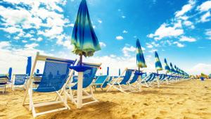 una fila di sedie e ombrelloni in spiaggia di RiminiMare House a Rimini