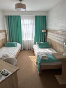 two beds in a room with green curtains at Diament i Brylant in Rawicz