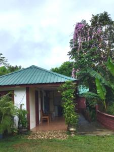 a small white house with a tree with purple flowers at D view hill hotel in Kuala Tahan