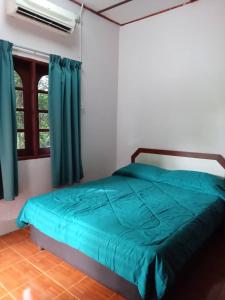 sypialnia z łóżkiem z niebieską pościelą i oknem w obiekcie D view hill hotel w mieście Kuala Tahan