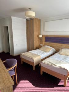a hotel room with two beds and a chair at Diament i Brylant in Rawicz