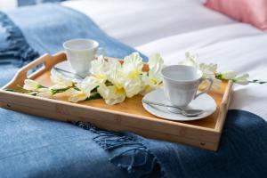 a tray with two cups and saucers on a bed at Cozy Studio Kwiatowa Poznań by Renters in Poznań