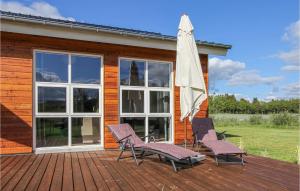 una terraza con 2 sillas y una sombrilla en Nice Home In Ejstrupholm With Sauna en Ejstrup