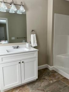 La salle de bains est pourvue d'un lavabo blanc et d'un miroir. dans l'établissement New luxury spacious 3BR 3BA 1 mile from Mt Snow, à Dover