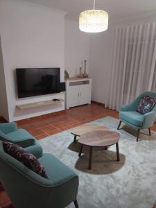 a living room with two chairs and a table and a tv at Casa com Alma by LovelyStay in Fátima