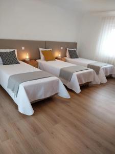 a row of beds in a room with wood floors at Casa com ALma in Fátima